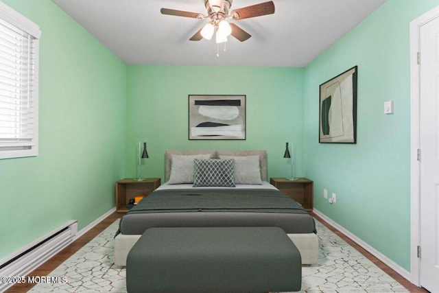 bedroom featuring ceiling fan, hardwood / wood-style floors, and a baseboard heating unit