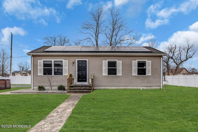 view of front of property featuring a front lawn and solar panels