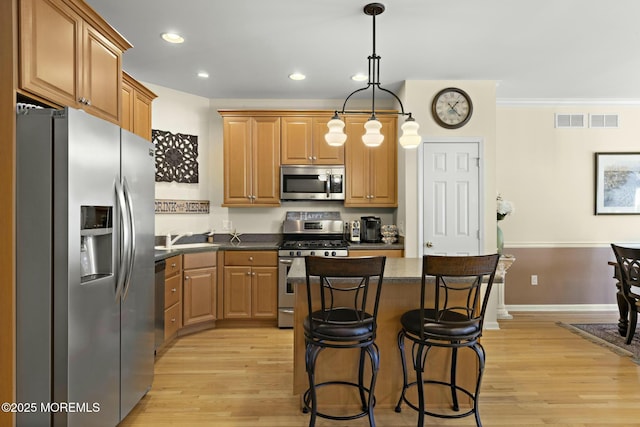 kitchen featuring stainless steel appliances, a center island, light hardwood / wood-style flooring, and decorative light fixtures