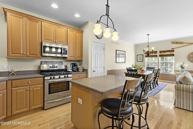 kitchen featuring a breakfast bar, an inviting chandelier, a kitchen island, pendant lighting, and stainless steel appliances