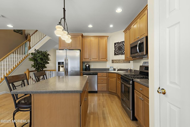 kitchen with a breakfast bar, decorative light fixtures, a center island, light hardwood / wood-style flooring, and stainless steel appliances