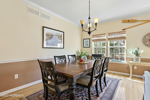 dining room with crown molding, light hardwood / wood-style floors, and a chandelier