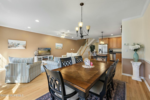 dining space with ornamental molding, ceiling fan with notable chandelier, and light hardwood / wood-style flooring