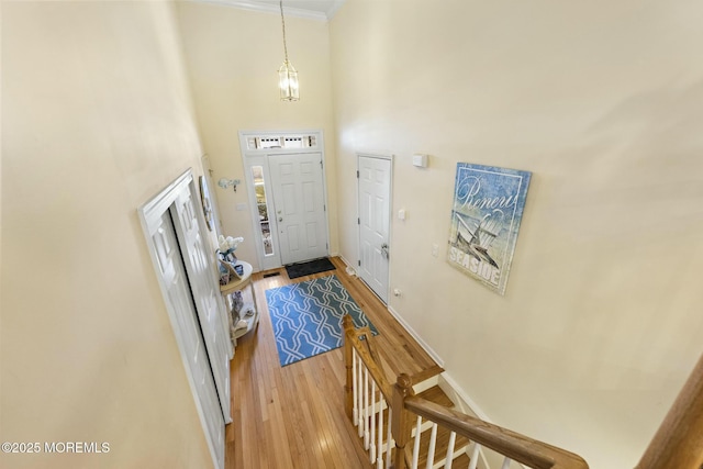 entrance foyer with crown molding, a notable chandelier, a towering ceiling, and wood-type flooring