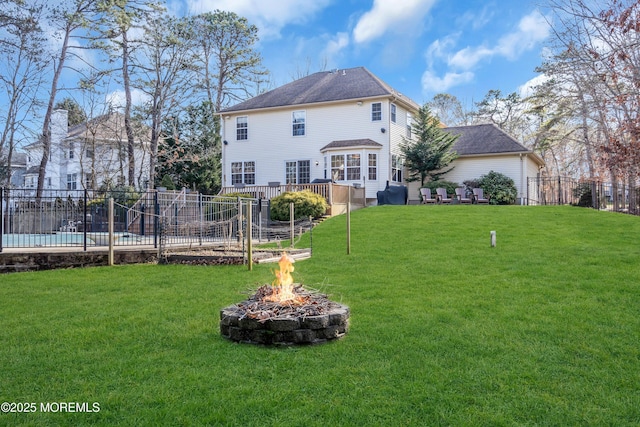 rear view of property with a yard and an outdoor fire pit