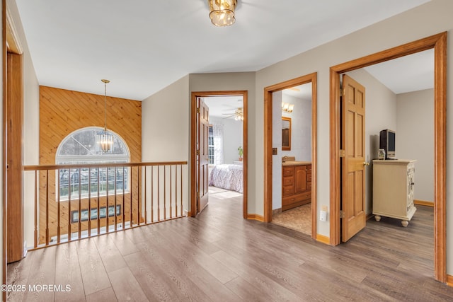 hall with an inviting chandelier, wood-type flooring, and wood walls