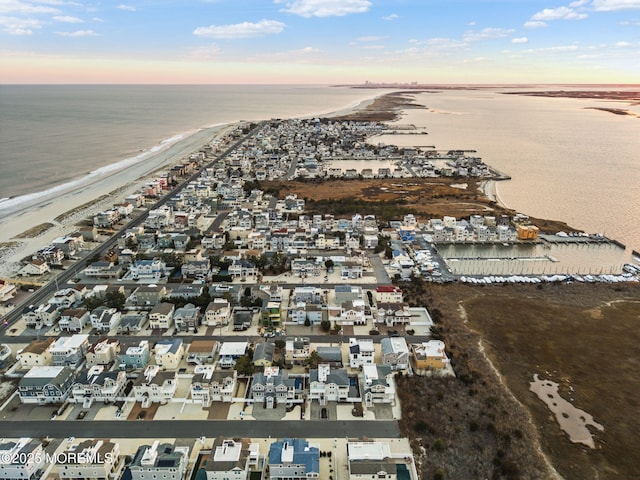 aerial view at dusk with a water view and a view of the beach