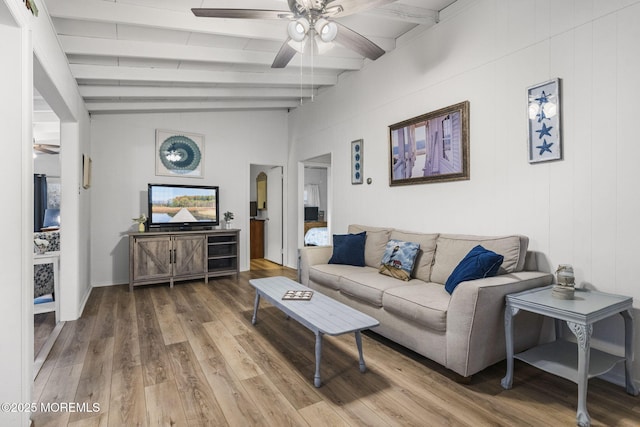 living room with ceiling fan, wood-type flooring, and lofted ceiling with beams