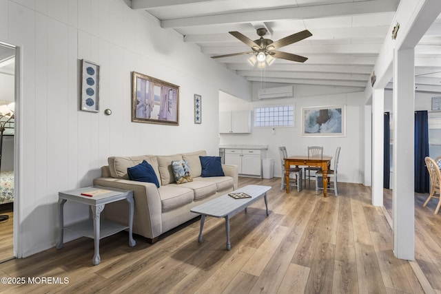 living room with vaulted ceiling with beams, ceiling fan, a wall mounted AC, and light wood-type flooring