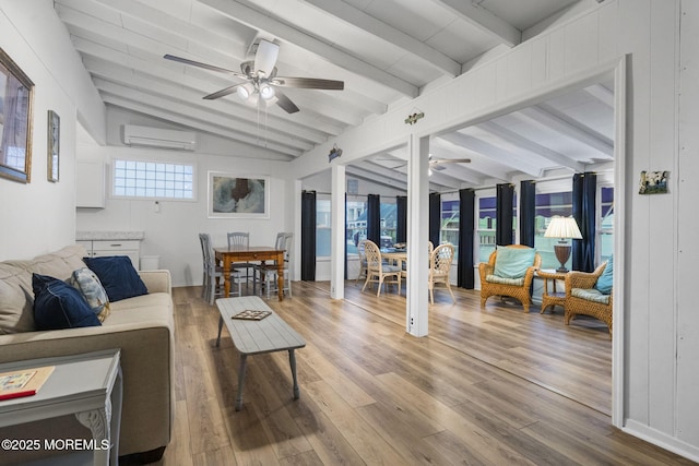 living room featuring hardwood / wood-style flooring, ceiling fan, lofted ceiling with beams, and a wall unit AC