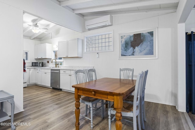 dining space featuring lofted ceiling with beams, a wall mounted air conditioner, light hardwood / wood-style floors, and sink