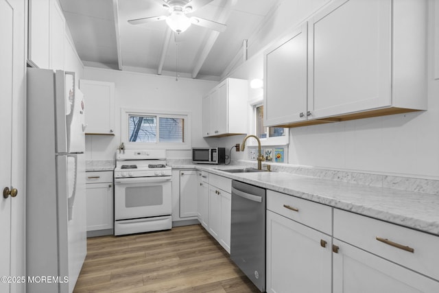 kitchen featuring sink, hardwood / wood-style flooring, appliances with stainless steel finishes, beam ceiling, and white cabinets