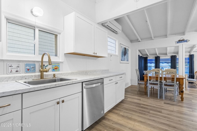 kitchen with sink, a wall mounted air conditioner, light hardwood / wood-style floors, white cabinets, and stainless steel dishwasher