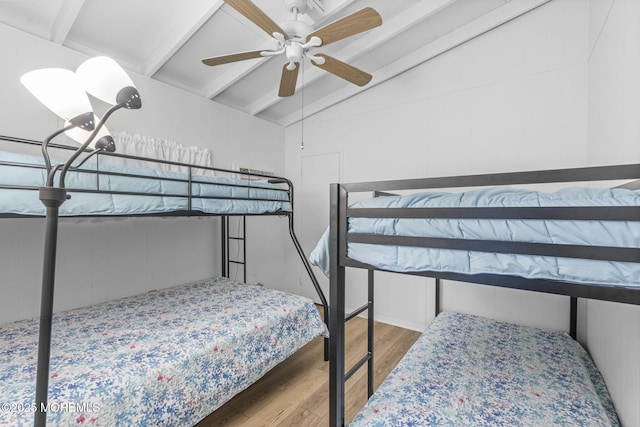 bedroom featuring ceiling fan, hardwood / wood-style floors, and vaulted ceiling with beams