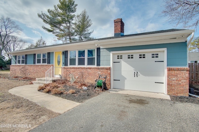 ranch-style home with a garage, driveway, brick siding, and a chimney