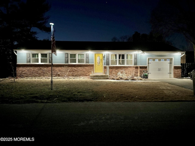 single story home featuring a garage, brick siding, and entry steps