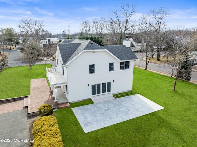 rear view of house featuring a patio, a balcony, and a lawn