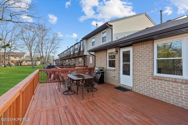 wooden terrace featuring a yard, outdoor dining space, and grilling area