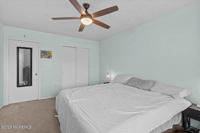 carpeted bedroom with a textured ceiling, ceiling fan, and a closet