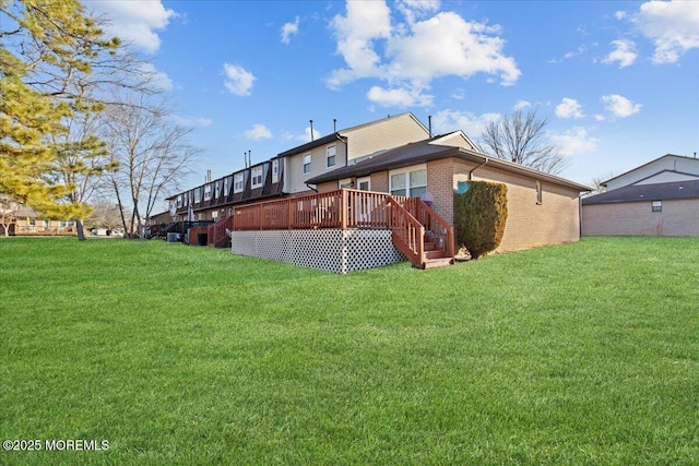 back of house featuring a deck, a yard, and brick siding