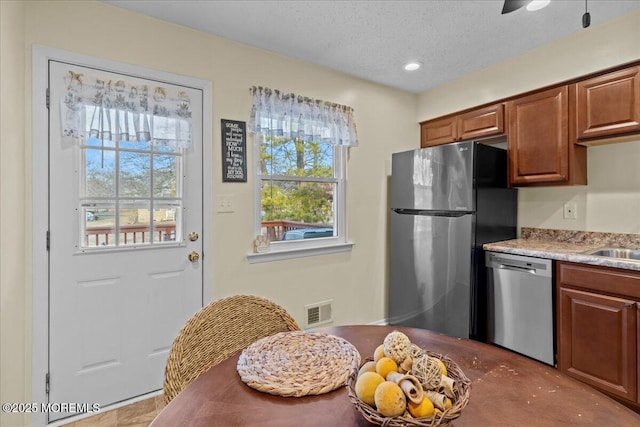 kitchen featuring visible vents, appliances with stainless steel finishes, brown cabinets, light countertops, and a textured ceiling