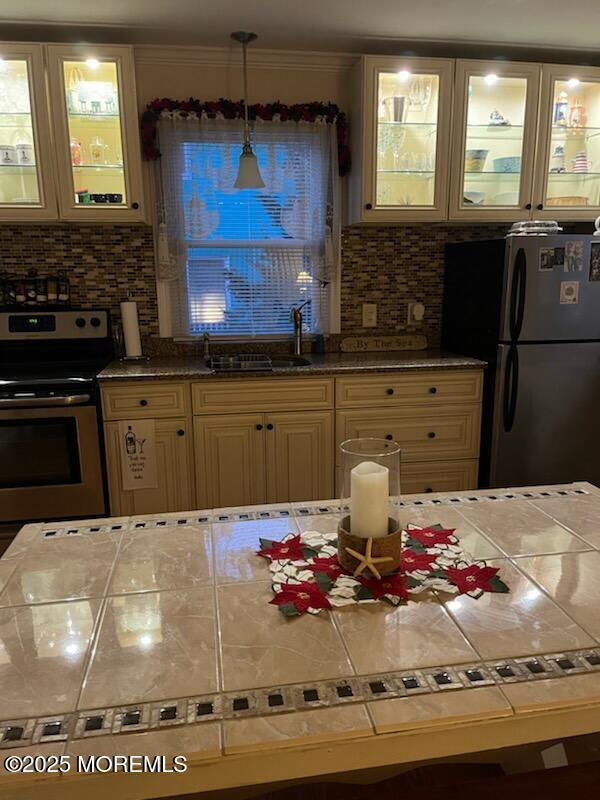 kitchen featuring pendant lighting, stainless steel appliances, sink, and backsplash