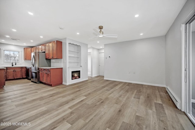 kitchen featuring freestanding refrigerator, light countertops, a sink, and baseboard heating