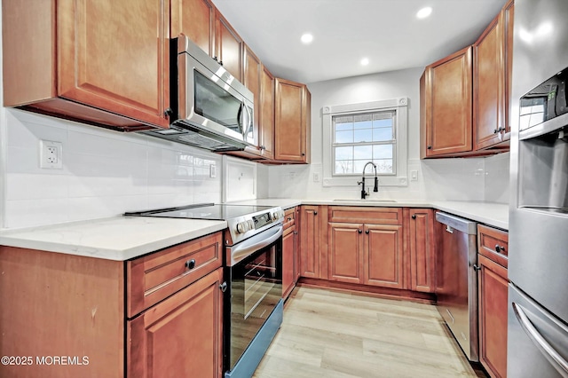 kitchen featuring recessed lighting, a sink, light wood-style floors, appliances with stainless steel finishes, and tasteful backsplash