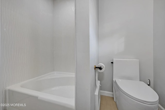 bathroom with toilet, baseboards, and a bathtub