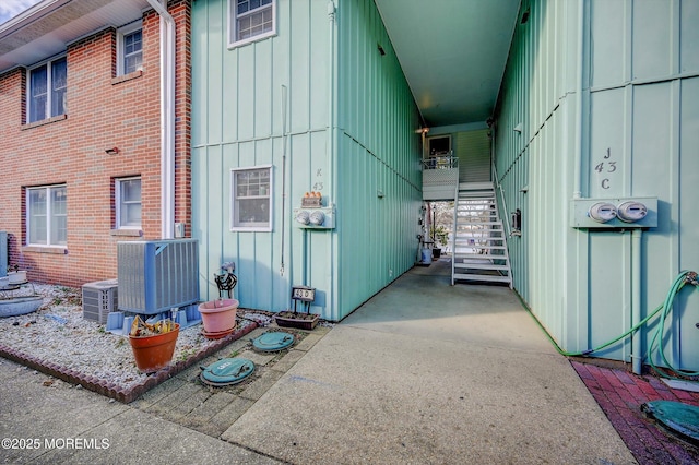 view of home's exterior featuring board and batten siding, cooling unit, and stairs