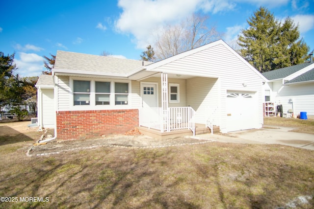 single story home featuring brick siding, concrete driveway, a shingled roof, a front yard, and a garage