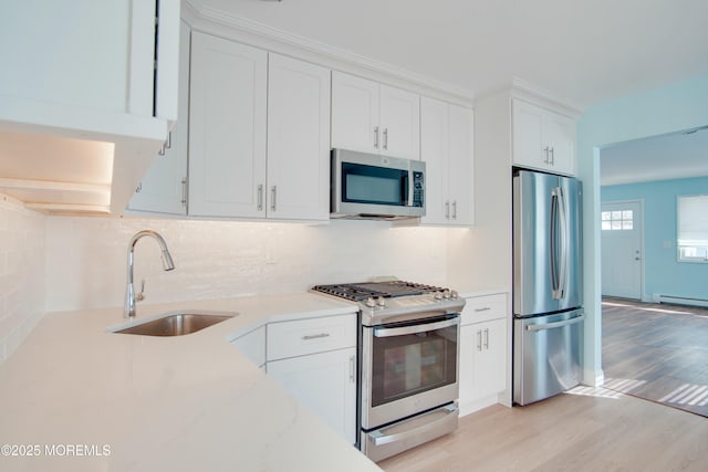 kitchen featuring decorative backsplash, light wood finished floors, a sink, white cabinetry, and appliances with stainless steel finishes