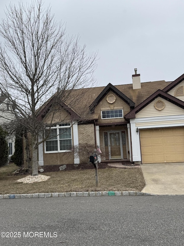 view of front of property featuring a garage, a chimney, and concrete driveway