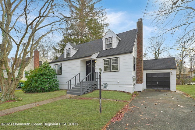 new england style home featuring a garage, an outbuilding, and a front lawn