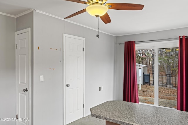 unfurnished dining area with ornamental molding, ceiling fan, and carpet