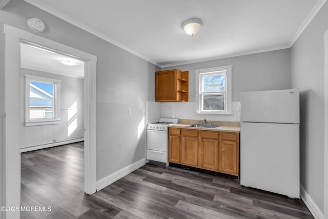 kitchen with sink, a wealth of natural light, white appliances, and baseboard heating