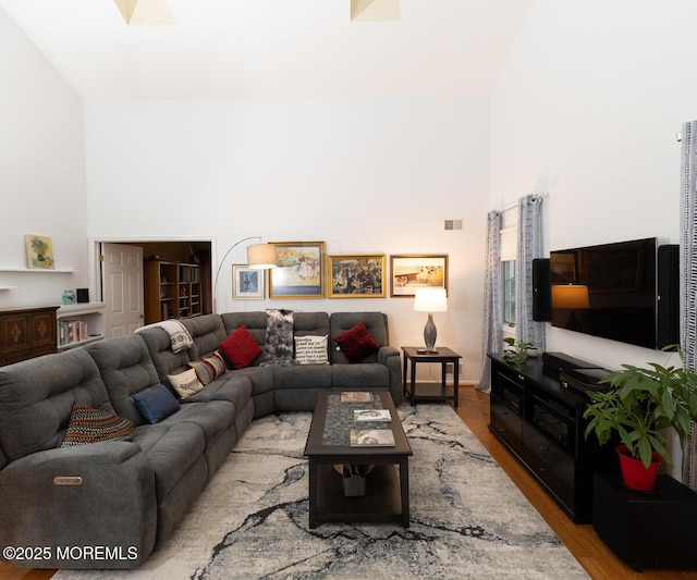 living area featuring visible vents, a towering ceiling, and light wood finished floors