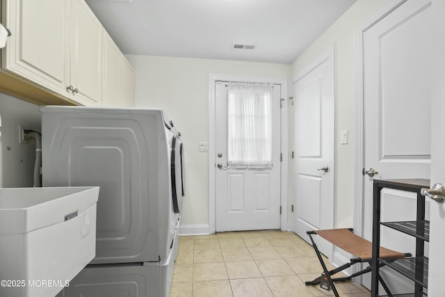 laundry area featuring washer / clothes dryer, cabinets, and light tile patterned flooring