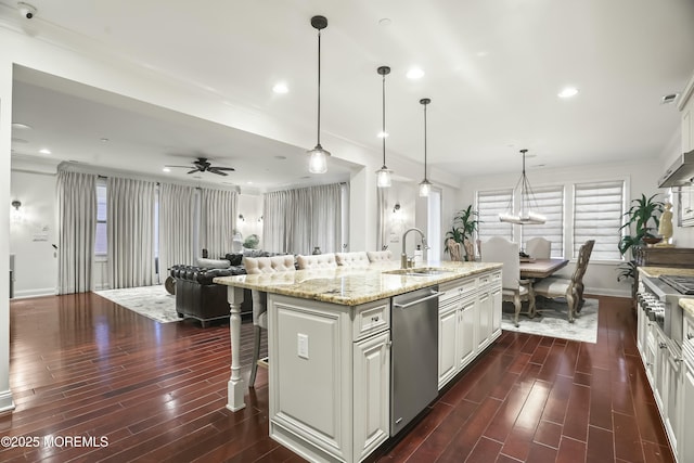 kitchen featuring sink, a kitchen island with sink, white cabinetry, stainless steel appliances, and decorative light fixtures