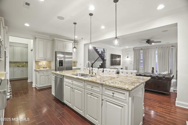 kitchen featuring pendant lighting, sink, appliances with stainless steel finishes, a center island with sink, and dark hardwood / wood-style flooring