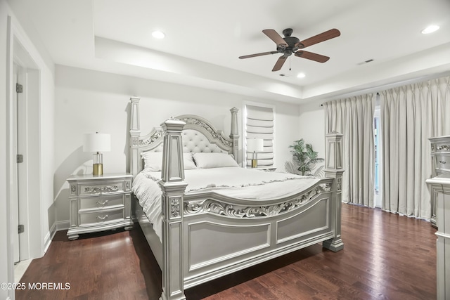 bedroom featuring dark wood-type flooring, ceiling fan, and a tray ceiling