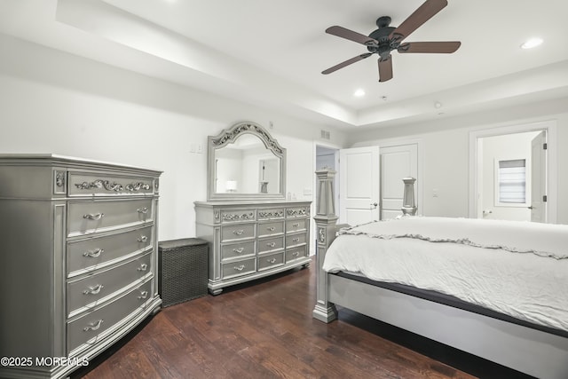 bedroom with a raised ceiling, ceiling fan, dark hardwood / wood-style flooring, and a closet