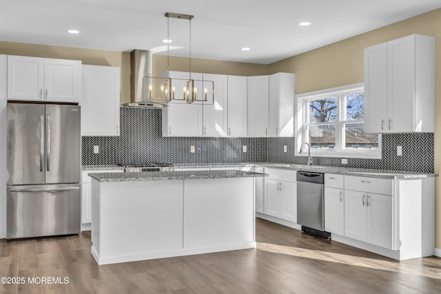 kitchen featuring pendant lighting, white cabinetry, range hood, stainless steel appliances, and a center island