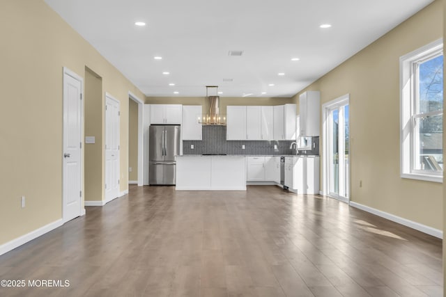 kitchen featuring stainless steel refrigerator, white cabinetry, a kitchen island, and pendant lighting