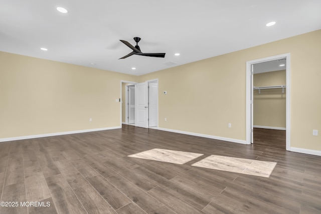 unfurnished bedroom featuring hardwood / wood-style flooring, a spacious closet, and ceiling fan