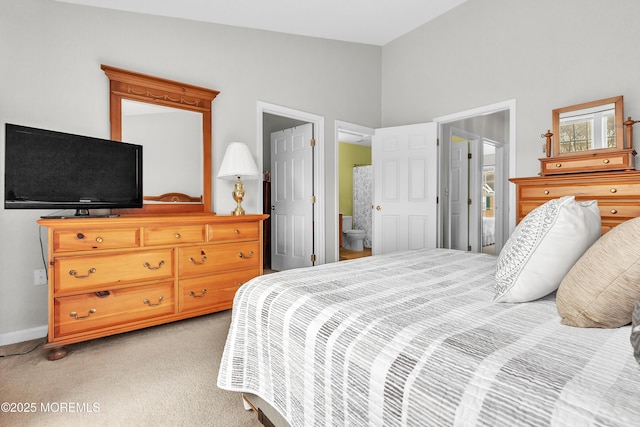 carpeted bedroom with ensuite bath and lofted ceiling