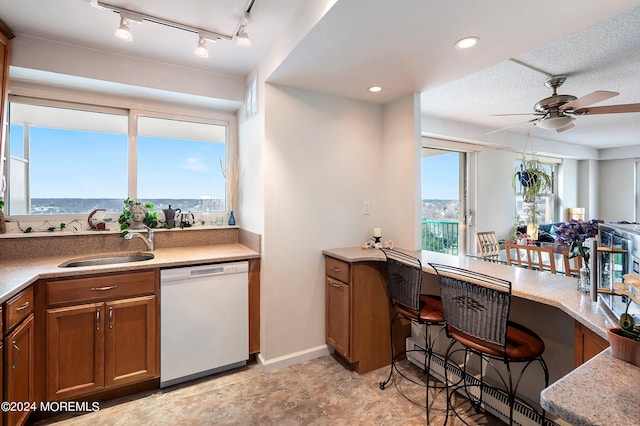 kitchen featuring ceiling fan, white dishwasher, a sink, light countertops, and brown cabinetry