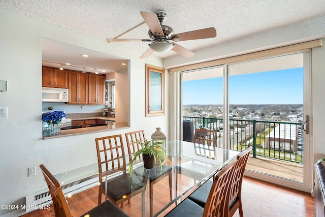 dining space with a ceiling fan, a textured ceiling, and light wood finished floors