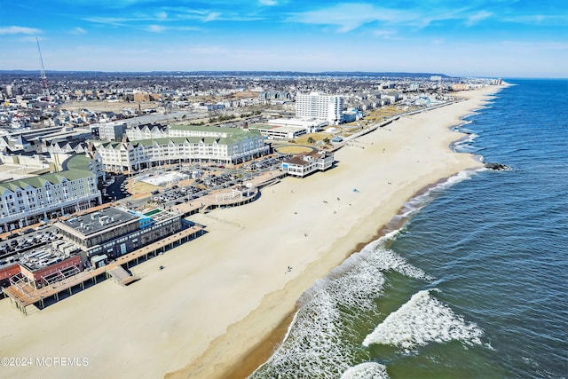 drone / aerial view featuring a water view, a view of the beach, and a city view