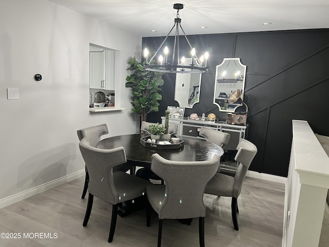 dining room featuring light wood-style flooring, baseboards, and an inviting chandelier